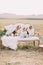 Three dogs are sitting on the old-fashioned sofa covered with the knitted plaid near the colourful bouquet at the