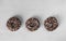 Three donuts covered with chocolate glaze on light gray background, Top view