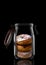 Three donuts in a glass storage or canning jar isolated on black with reflection, with lid open