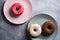 Three donuts on plates, chocolate, pink and vanilla donut with sprinkles, sweet glazed dessert food