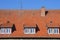 Three dormer windows with tides in a house with a tiled roof. Against the background of the blue sky