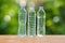 Three drinking water bottles on wooden table on blurred green bokeh background