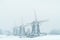 Three Dutch windmills during snowfall