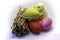 Three Easter colored eggs a bundle of firewood and a chicken on a light background