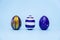 Three easter trendy colored classic blue and golden decorated eggs striped pattern on blue. Happy Easter card with copy