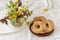 Three eclair rings on saucer, light background, next to spring flowers in a vase. Spring, sweet food, bakery dessert