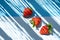 Three ecological strawberries on a blue background