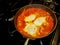 Three egg shakshuka cooking in an iron skillet on a stovetop