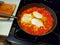 Three egg shakshuka cooking in an iron skillet on a stovetop