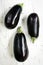 Three Eggplants on White Timber