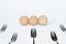 Three eggs and five forks on a white background