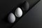 Three eggs in a monochrome palette with a speckled egg in focus are set against a dark background. The somber mood