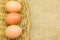 Three eggs in wicker basket on gunny sack background