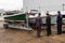 Three elderly men standing next to newly restored wooden boats on a slipway