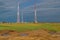 Three elecommunication towers white red color construction stands against in green field with yellow green grass, water puddles