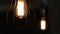 Three electric lamps are hung on ceiling burns in darkness