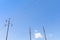 Three electrical power poles side by side, strain insulators, against a blue sky