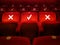 Three empty red velvet armchairs illuminated inside a concert hall