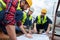 three engineers in hardhats working with blueprints