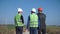 Three engineers walking against wind farm