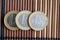 Three euro coins lie on wooden bamboo table in a row Denomination is one euro