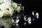 Three excellent diamonds of the first water and bouquet of white roses with reflection on black mirror background close up view.