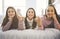 Three excited teenager girls having fun together enjoying laze leisure time on bed