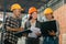 three factory employees stand at work matching data and using a laptop