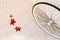 Three fallen red maple leaves on the marble floor and a white bicycle wheel.