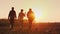 Three farmers go ahead on a plowed field at sunset. Young team of farmers