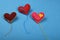 Three felt craft art hearts with threads on blue