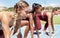 Three female athletes at the starting line in a track race competition at the stadium. Young sporty women in a race