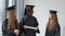 Three female caucasian and african american students with a diploma in their hands. Graduates in black robes and square