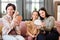 Three females doing makeup while sitting on sofa