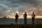 Three fishermen at the sunset lights standing on the Malecon street with sea and city in the background