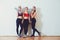 Three fitness young girls in sportswear standing against wall in fitness gym. Girls smiling and looking to camera.