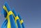 Three flags of Sweden on a flagpole on a blue background. Place for text. The flag is unfurling in wind. Swedish. Europe,