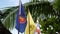 Three flags waving against tropical leaves. Symbol of ASEAN fluttering near flags of Thailand and Thai King against