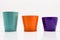 Three flower pots in turquoise, orange and purple colors isolated on a white background with a clipping path.