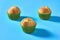 Three fluffy muffins in green paper mold on blue