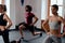 Three focused multiracial young adults in sportswear doing lunges at the gym