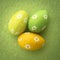Three foil wrapped easter eggs on green surface