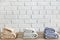 Three folded bath towels on wooden table and white brick wall on background. Beige, lavender and mint colors