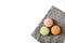 Three france cakes on grey kitchen towel. Towel with ornament lines, boxes. Macaroons on table. Green, pink and orange sweets in c
