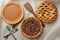 Three fresh baked holiday pies, Apple, Pecan and Pumpkin on a burlap table cloth. Horizontal format with forks and wooden spatula