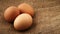 Three fresh brown chicken eggs rotating on burlap fabric background