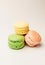 Three fresh colored macaroons lie in a heap in the center. Meringue on an isolated background with copy space