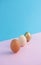 Three fresh eggs and a third painted gold on a light pastel pink and blue background. Minimal Easter creative design.