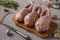 Three fresh raw organic quails on wooden board on a gray background, Closeup, Horizontal format