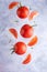 Three fresh red tomatoes with micro greens on a gray background, top view, close up